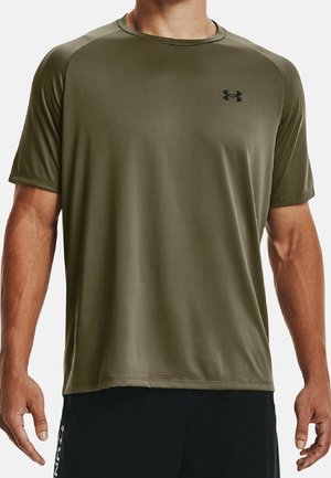 Mann trägt olivgrünes kurzärmeliges Sportshirt mit Under Armour-Logo auf der Brust und schwarze Shorts.