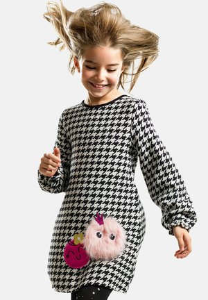 Kleid im schwarz-weißen Pied-de-Poule-Muster, verziert mit einem pinken, flauschigen Element mit Augen und einer Krone sowie einem runden, pinken Akzent.