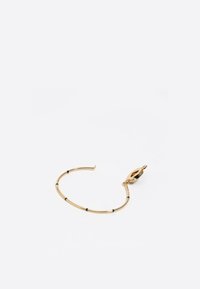 Pulsera de oro con un diseño suave, detalles en negro, cierre ovalado y una forma flexible y alargada con una textura discreta.