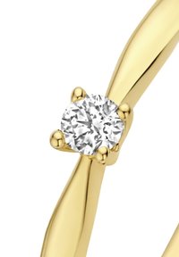 Gouden ring met een ronde, heldere diamant in een vierpunkts zetting. De band heeft een glad, gedraaid ontwerp met een gepolijste afwerking.