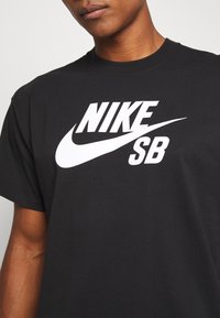 Black cotton t-shirt featuring a large white Nike SB graphic logo across the chest and standard crew neckline. Soft texture.