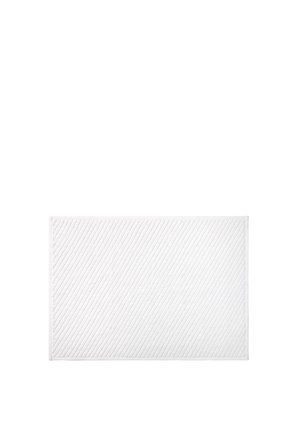 Tapis de bain rectangulaire blanc avec de subtiles lignes texturées en diagonale, posé à plat sur un fond blanc uni. Aucun autre objet présent.