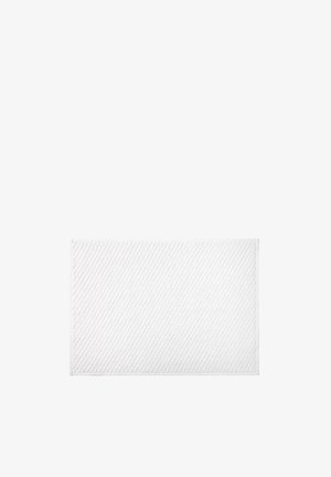 Tapis de bain rectangulaire blanc avec de subtiles lignes texturées en diagonale, posé à plat sur un fond blanc uni. Aucun autre objet présent.