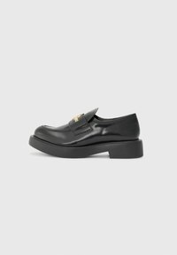 Black patent leather shoe with a rounded toe, low platform sole, and a decorative strap featuring gold hardware. Smooth texture and minimal design.
