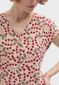 Abito a stampa floreale in rosa chiaro con foglie rosso scuro e verdi. Presenta un collo a V, maniche corte e bottoni bianchi sul davanti.