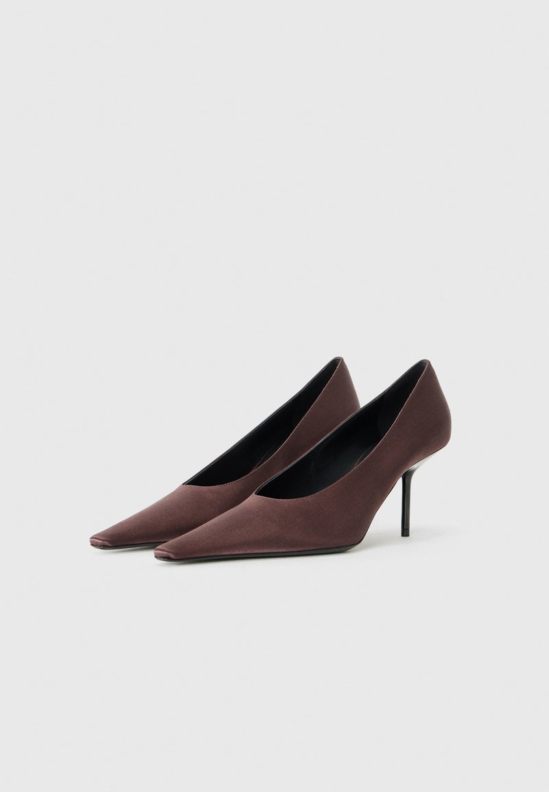 Brune ruskind stiletto-pumps med spids tå og en slank sort stiletthæl samt en elegant, strømlinet silhuet. Glat tekstur, minimalistisk design.