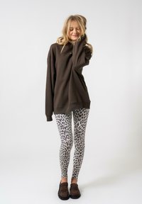 Barna, túlsúlyos pulóver, szürke állatmintás leggings és barna slip-on cipők. Simább anyag, laza fazon és hosszú ujjak.