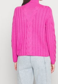 Pull à col montant côtelé fuchsia avec détails en maille torsadée le long du dos et des côtés, manches longues et coupe décontractée.