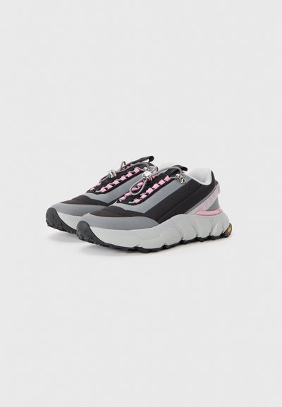 Sport shoes featuring a mix of black, grey, and pink materials, with a chunky silhouette, cushioned soles, and distinctive lacing system.