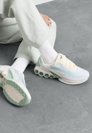 Leichte Sportschuhe mit einem Obermaterial aus Netzgewebe in Hellblau und Off-White, ausgestattet mit einer strukturierten Sohle, grünen Akzenten und gepolstertem Absatz.
