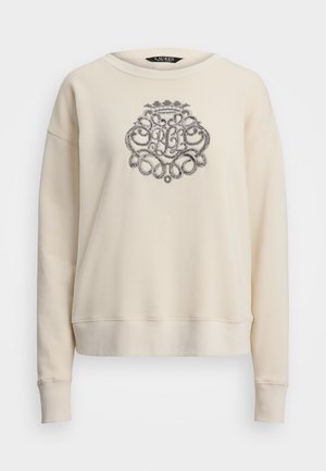 Sudadera color crema con escote redondo, mangas largas y un diseño de logotipo bordado en plata texturizada en la parte frontal.