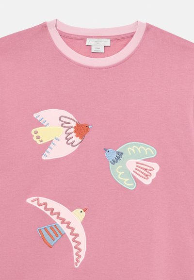 Ροζ βαμβακερό μπλουζάκι με πολύχρωμα κεντημένα πουλιά σε διάφορα σχέδια. Διακοσμείται με ένα αντίθετο ανοιχτό ροζ ριμπ λαιμό.
