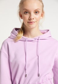 Lila hoodie med dragsko, som har en mjuk textur och elastisk midja. Huvan har en slät innerfoder.