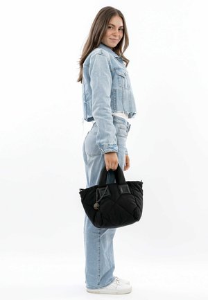 Black quilted handbag with dual handles and a shiny chain accent; paired with a light blue cropped denim jacket and matching jeans.