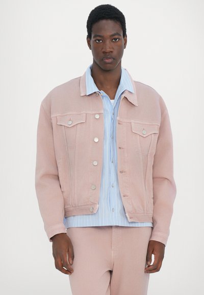 Light pink denim jacket with silver hardware, featuring a collar and chest pockets, layered over a light blue striped shirt.