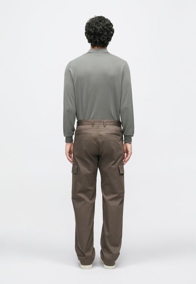 Γκρι μπλούζα με μακριά μανίκια και καφέ cargo παντελόνι. Η μπλούζα διαθέτει στρογγυλή λαιμόκοψη, ενώ το παντελόνι έχει πλαϊνές τσέπες και χαλαρή εφαρμογή.