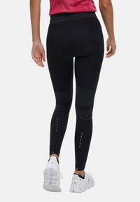 Zwarte leggings met een textuurdesign en contrasterende panelen. Reflecterende accenten zijn zichtbaar nabij de enkels. Gemaakt van rekbaar materiaal.