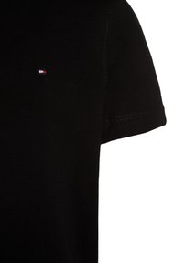 T-shirt en coton noir avec un col rond et des manches courtes. Présente un petit logo brodé en rouge, blanc et bleu sur la poitrine.