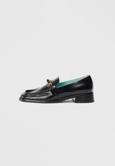 Mocassino in pelle nera con tacco basso, caratterizzato da un design cucito, un accento in metallo dorato e una fodera interna turchese.