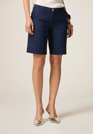 Pantaloni corti blu navy realizzati in tessuto leggero, con taglio dritto, tasche laterali e chiusura a bottone con una texture liscia.