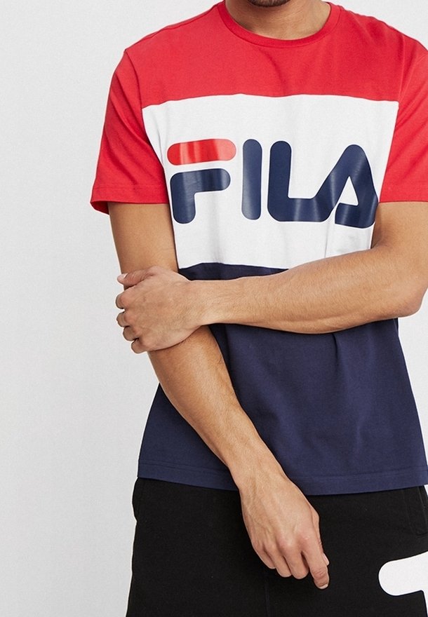 T-shirt à manches courtes rouge, blanc et bleu présentant un grand logo FILA sur la poitrine ; fabriqué en coton doux avec une coupe décontractée.