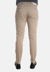 Pantaloni khaki dal taglio slim, realizzati in tessuto leggero e dotati di tasche posteriori; abbinati a scarpe nere.
