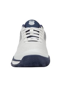 Pantofii sport albi au un superior din material texturat, accente bleumarin și o talpă cu un model. Au șase orificii pentru șnururi și un logo pe limbă.