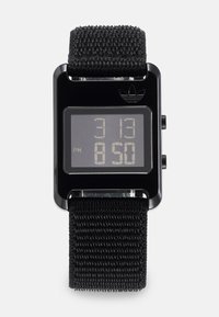 Orologio digitale con quadrante rettangolare nero, display digitale che mostra l'ora in bianco e un cinturino in tessuto nero texturizzato. Logo Adidas in cima.