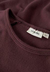 Felpa in cotone bordeaux con finitura testurizzata, dotata di scollo rotondo e un'etichetta interna che recita "Lil' Atelier."