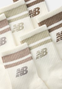 Bavlnené ponožky s krátkym strihom v krémovej farbe s hnedými a olivovými pruhmi. Obsahujú rebrovanú textúru a logo "NB" v sivej farbe na každej ponožke.