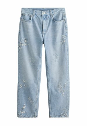 Hellblaue Jeans aus Denim mit kleiner weißer Blumenstickerei auf der Tasche und am Oberschenkel, kombiniert mit einem weißen strukturierten Langarmtop.