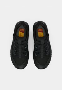 Sapatilhas atléticas pretas com um superior texturizado, detalhes refletivos e sola de borracha. Apresentam atacadores elásticos e palmilha almofadada.