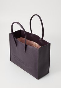 Purple leather tote bag with two handles, textured exterior, open top, and a light pink interior. Features embossed brand name on the side.