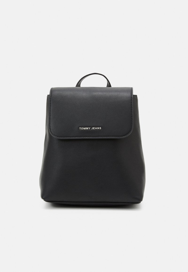 Sac à dos en cuir noir avec fermeture à rabat et logo "TOMMY JEANS" en argent au centre avant, présenté sur un fond uni.