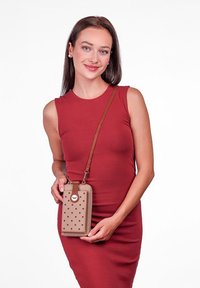 Beige crossbody bag with polka dot texture, brown strap, and circular hardware detail. Simple rectangular shape with smooth finish.