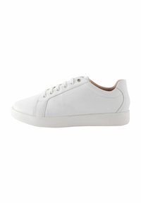 Baskets en cuir blanc avec une texture lisse, bout arrondi, six œillets pour les lacets et un design minimaliste. La semelle en caoutchouc offre une bonne adhérence.