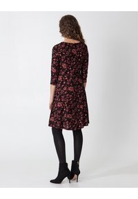 Black floral dress with three-quarter sleeves, flared skirt, and a fitted waist. Pair with black ankle boots and tights.