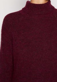 Burgundy stickad tröja, mjuk textur, hög krage, lös passform, ribbat mönster, medeltjockt tyg, inga synliga knäppningar eller mönster.