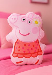 Cuscino morbido rosa a forma di maialino dei cartoni animati, con un viso sorridente, un vestito rosso a pois e un accento floreale sulla testa.