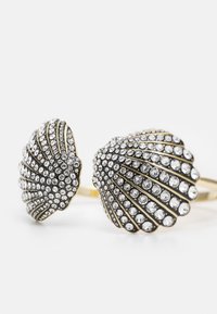 Goldfarbener Manschettenarmreif mit zwei muschelförmigen Enden, die jeweils mit Reihen klarer Strasssteine in Fächerform verziert sind.