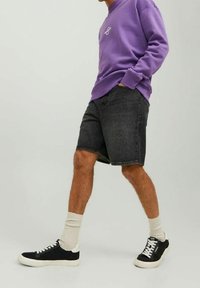 Felpa viola, pantaloncini di jeans grigi, scarpe da ginnastica nere con accenti bianchi e calzini crema. Design semplice, vestibilità standard, estetica casual.