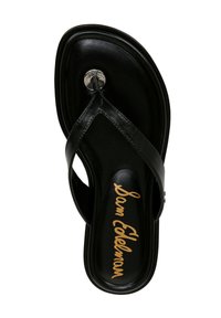 Sandale en cuir noir avec semelle plate, dotée d'un accent métallique circulaire et d'une lettre dorée sur la semelle intérieure.