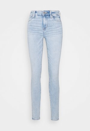 Heledad sinine kitsas teksapüksid, mis on valmistatud denimist, kõrge vöökoht, esikotid ja sile, veidi pleekinud tekstuur. Hõbedane nööp kinnitamiseks.