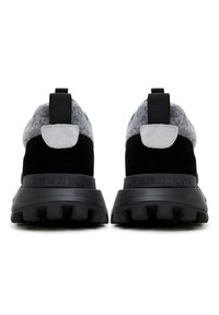 Paire de baskets noires et grises vues de dos, avec des semelles épaisses et des marquages de taille numérotés sur la semelle intermédiaire.