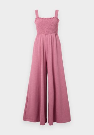 Pink jumpsuit with smocked bodice and ruffled neckline. Wide-leg design and soft, textured fabric. Adjustable shoulder straps.