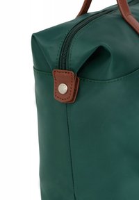 Zielona wodoodporna torba o gładkiej teksturze, z brązowymi skórzanymi akcentami i górnym zamkiem błyskawicznym. Do wyróżniających się szczegółów należą zatrzask i estetyczne szwy.
