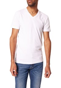Weißes Baumwoll-T-Shirt mit V-Ausschnitt. Kurze Ärmel und eine normale Passform. Kombiniert mit blauen Jeans, was ein lässiges Ensemble ergibt.