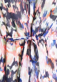 Vestido multicolor con un vibrante patrón abstracto en tonos de rosa, azul y verde, con un detalle de cintura anudada y tejido ligero.