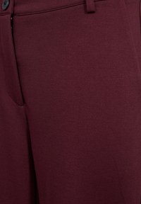 Burgundy trousers with a smooth, textured fabric. Features a button closure and a side pocket, displaying a tailored design.