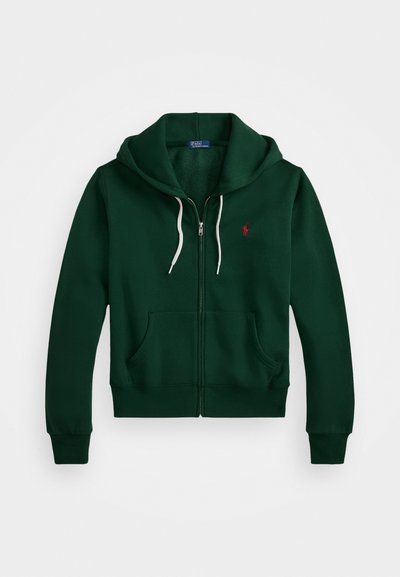 Sweatshirt verde com fecho na frente, cordões brancos, dois bolsos frontais e um pequeno emblema vermelho no lado esquerdo do peito. Tecido em mistura de algodão.